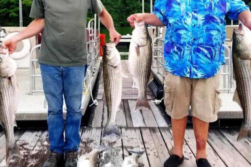 two men holding fish in a basket on a deck at Lakefront: Dock, Hot Tub, Fire Pit & Home Theater in Winchester