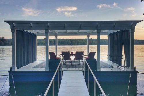 a dock with a table and chairs on the water at Lakefront: Dock, Hot Tub, Fire Pit & Home Theater in Winchester