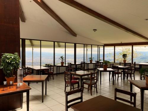 un restaurant avec des tables, des chaises et des fenêtres dans l'établissement Hotel Colinas Altavista, à Tarbaca