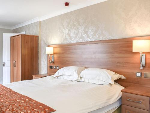 een slaapkamer met een groot bed met een houten hoofdeinde bij Kemps House in East Stoke