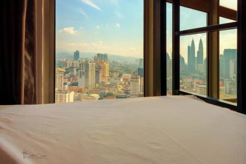 a bed in a room with a view of a city at The Common Room @ Regalia in Kuala Lumpur