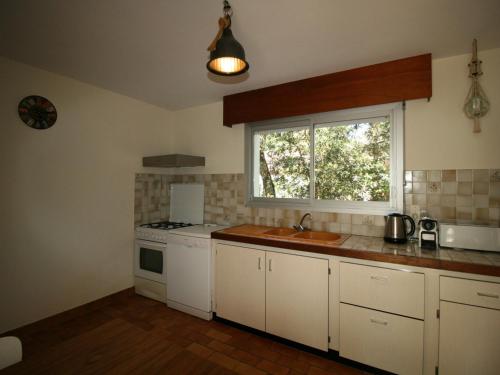 une cuisine avec un évier, une cuisinière et une fenêtre dans l'établissement Villa avec jardin boisé, proche plage et commerces, La Tranche-sur-Mer - FR-1-22-307, à La Tranche-sur-Mer