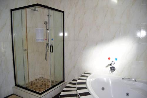 a bathroom with a shower and a bath tub at Homey Guesthouse in Gaborone