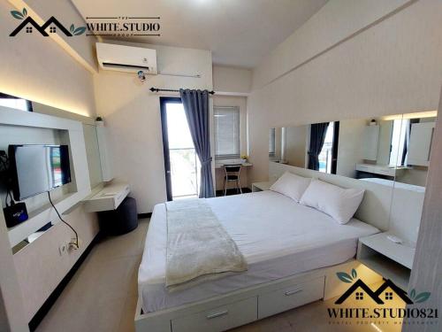 a bedroom with a large white bed and a desk at White Studio Group Surabaya - WS 821 at Amega Crown Residence in Tambakoso