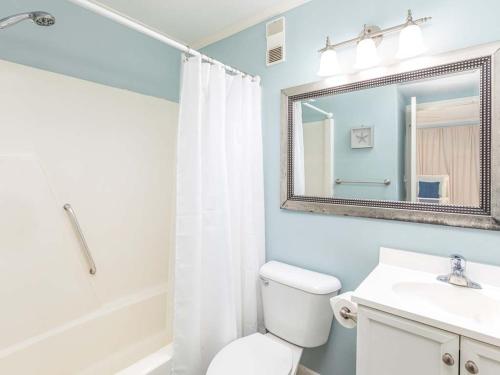 a bathroom with a toilet and a sink and a mirror at Beach Racquet A315 in Tybee Island