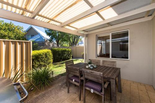 a patio with a wooden table and chairs under a pergola at FiftyTwo at Cape View in Busselton