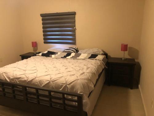 ein Schlafzimmer mit einem Bett und zwei Nachttischen mit Lampen in der Unterkunft Casa col mexicali in Rosarito