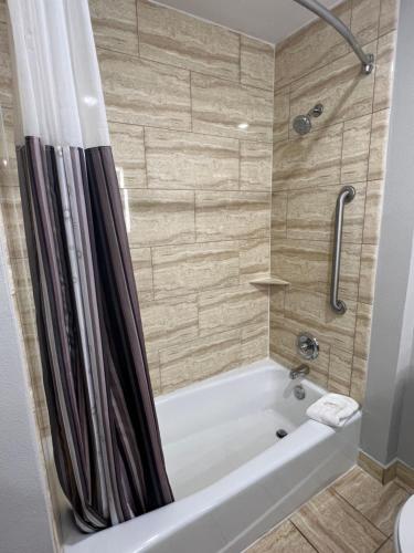 a bathroom with a white tub and a shower at La Quinta by Wyndham Allen at The Village in Allen