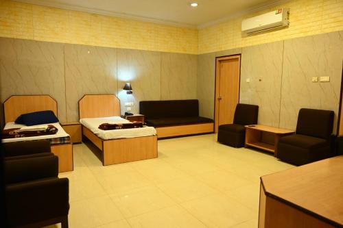 um quarto com duas camas e um sofá e cadeiras em Hotel Komala Vilas em Calcutá