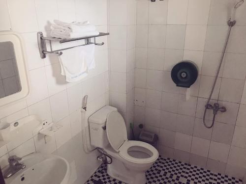 a white bathroom with a toilet and a sink at Lam Hong Hotel in Xuân Ðài