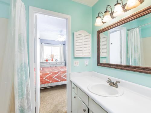 a bathroom with a sink and a mirror and a bedroom at Tybee Lights 110C in Tybee Island