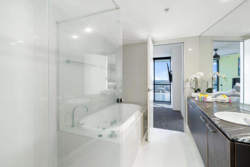 a white bathroom with a tub and a sink at Avalon Apartments - Wow Stay in Gold Coast