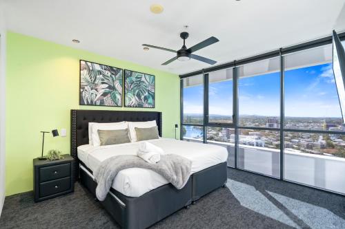 a bedroom with a large bed and glass windows at Avalon Apartments - Wow Stay in Gold Coast