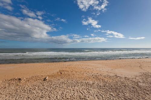 a sandy beach with the ocean on a cloudy day at SouthernVilla Ticket to Paradise in Palm Coast