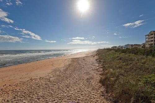 a sandy beach with the sun in the sky at SouthernVilla Ticket to Paradise in Palm Coast
