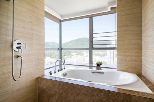 a bath tub in a bathroom with a large window at The LA Hotel 新世界伟瑞酒店 in Shenzhen