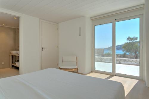 a bedroom with a bed and a large window at Beachfront Mykon Villa in Platis Gialos