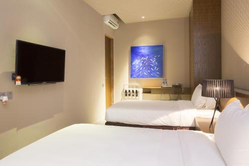 a hotel room with two beds and a flat screen tv at Silalima in Kuantan
