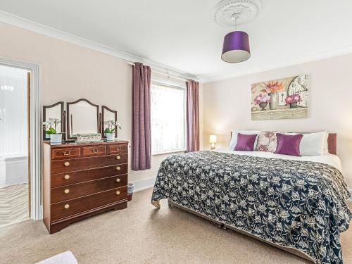 1 dormitorio con cama, tocador y espejo en Cosy Cottage, en Lyndhurst