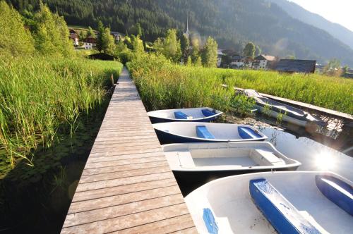 three boats are docked next to a wooden dock at Appartements Herwig Schwarzenbacher in Weissensee