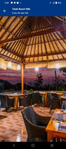 a restaurant with tables and chairs under a roof at Tatak Bunut Villa Ceningan in Nusa Lembongan