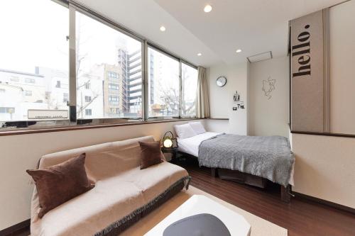 a living room with a couch and a bed and windows at ZEROSHARE CHIKKO in Osaka