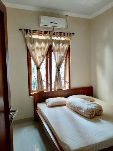 a bedroom with a bed and a window with curtains at Joglo Rahayu Homestay in Timuran