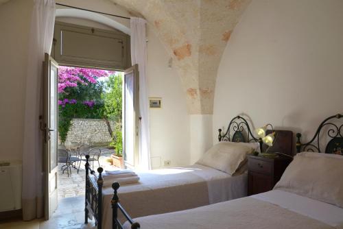 a bedroom with two beds and an open window at Masseria Lamiola Piccola in Ostuni