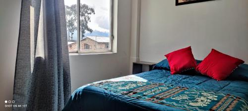 a bedroom with a bed with red pillows and a window at HOSPEDAJE DON PABLO in Otavalo