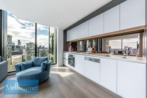 a kitchen with white cabinets and a blue chair at Melbourne Private Apartments - Collins Wharf Waterfront, Docklands in Melbourne