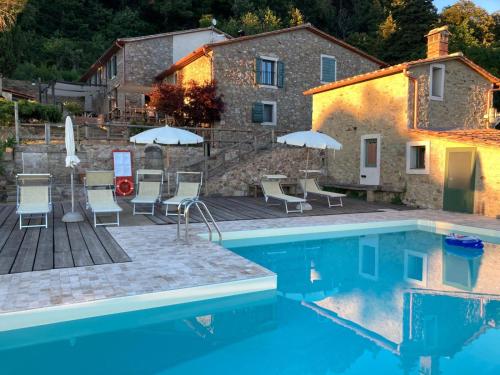 a pool with chairs and umbrellas in front of a house at B&B Podere Camaiano in Roccastrada