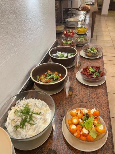 a buffet line of bowls of food on a counter at Hotel LukasMayr in Bruck an der Großglocknerstraße
