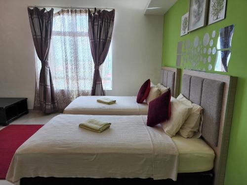 Duas camas num quarto com paredes verdes e uma janela em The Viana Apartment IV em Kota Bharu