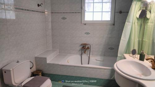 een badkamer met een bad, een toilet en een wastafel bij Christina's House in Chrysoupolis