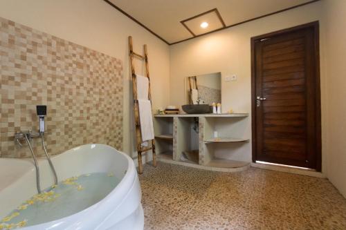 a bathroom with a bath tub and a sink at The Kayuan in Kintamani