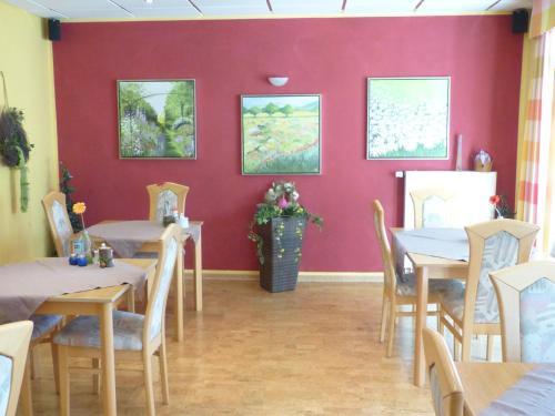 a restaurant with tables and chairs and a red wall at Gästehaus Steker in Bad Driburg