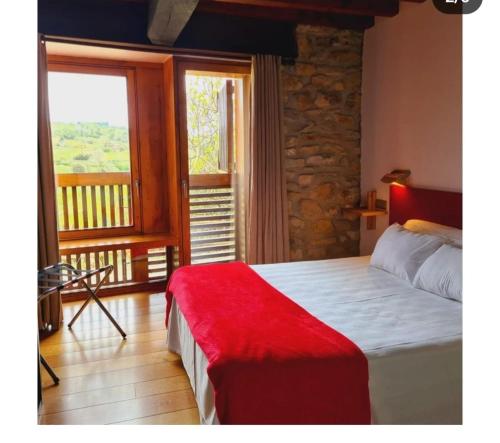 a bedroom with a bed and a large window at Posada Los Calderones in Santillana del Mar