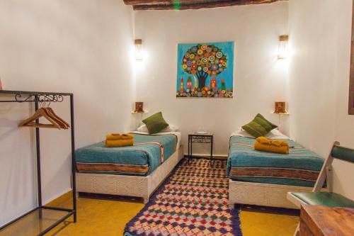 a room with two beds and a painting on the wall at Riad Dar Abi in Essaouira