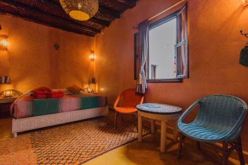 a bedroom with a bed and two chairs and a window at Riad Dar Abi in Essaouira