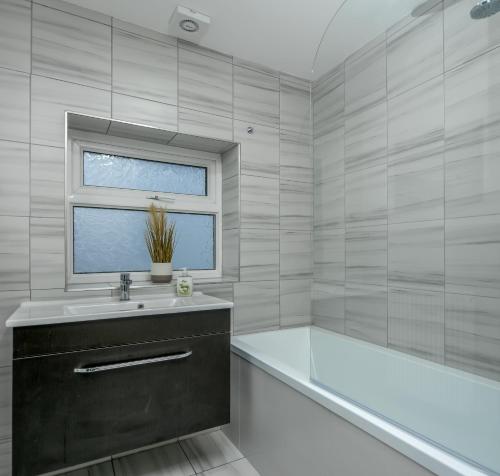 a bathroom with a tub and a sink and a window at Apex Living NE - Carnegie House 4 Bed House, FREE PARKING FREE WiFi in Ryhope