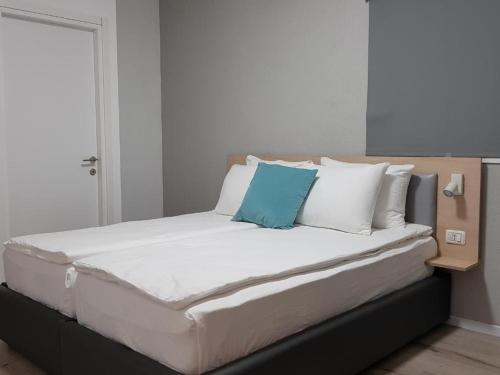 Una cama grande con almohadas blancas y azules. en Airport Guest House en Or Yehuda