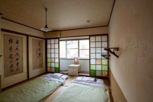 two beds in a room with a window at Guesthouse Bon in Kyoto