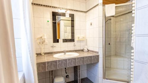 a bathroom with a sink and a shower at Aktivhotel & Gasthof Schmelz Ihr familienfreundliches Urlaubs Hotel mit Wellness Hallenbad, Alpensauna neu ab Februar 2026 Chiemgau Karte in Inzell
