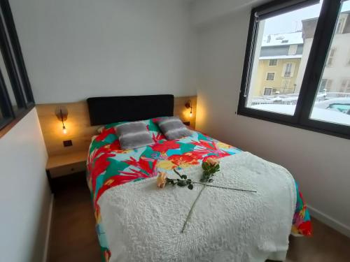 um quarto com uma cama com um edredão colorido e uma janela em Magnifique 3 étoiles en hyper centre avec place privée em Aix-les-Bains