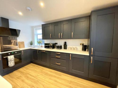 a kitchen with black cabinets and a wooden floor at Ivory House in Gorleston-on-Sea