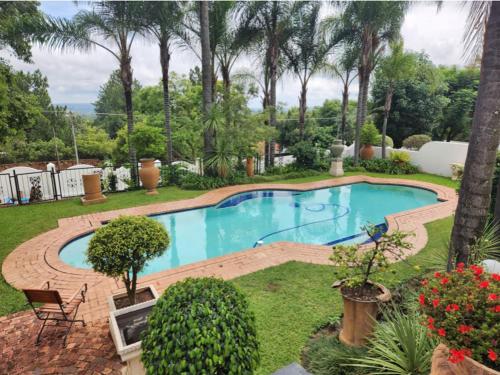 einen Pool in einem Garten mit Palmen in der Unterkunft Waterkloof Mansion Boutique Hotel in Pretoria