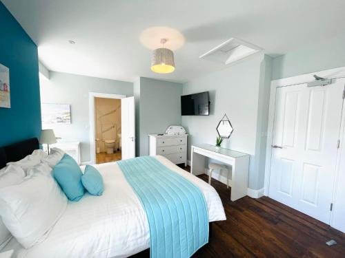 a bedroom with a bed with blue pillows and a desk at Coral House in Gorleston-on-Sea