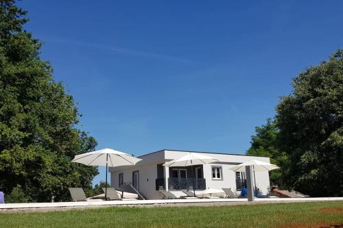 a white house with chairs and umbrellas at Luxury Villa Četiri Hrasta in Pićan