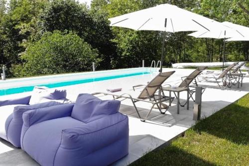 a purple couch and chairs and an umbrella next to a pool at Luxury Villa Četiri Hrasta in Pićan