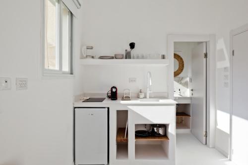 uma cozinha branca com um lavatório e um espelho em Isla apartment's em Tel Aviv